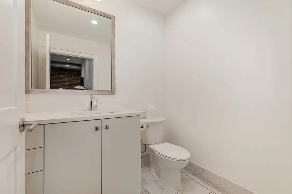 A modern bathroom showcases a sleek vanity with a large mirror and minimalistic decor. The calm ambiance and clean design offer a serene spot for personal care and self-reflection.
