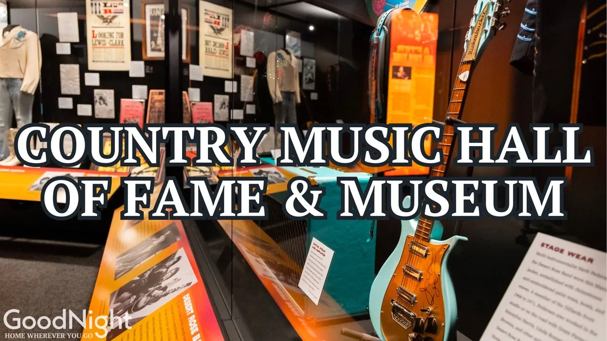 This image features a display of music memorabilia, including a guitar, stage wear, and historical posters, creating an immersive music history experience. The setup invites viewers to explore country music legends and iconic performances.